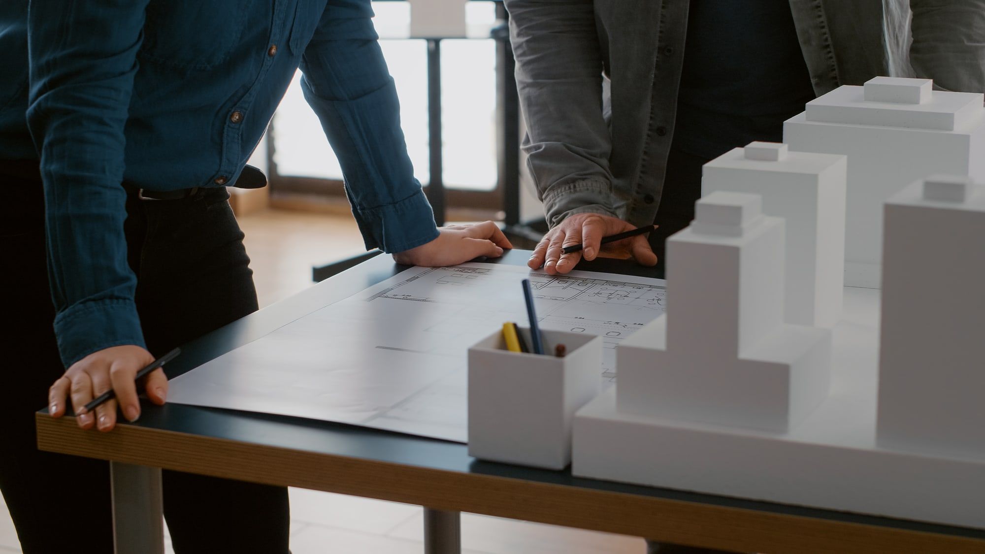 Team bespricht Pläne an einem Tisch mit Architekturmodell